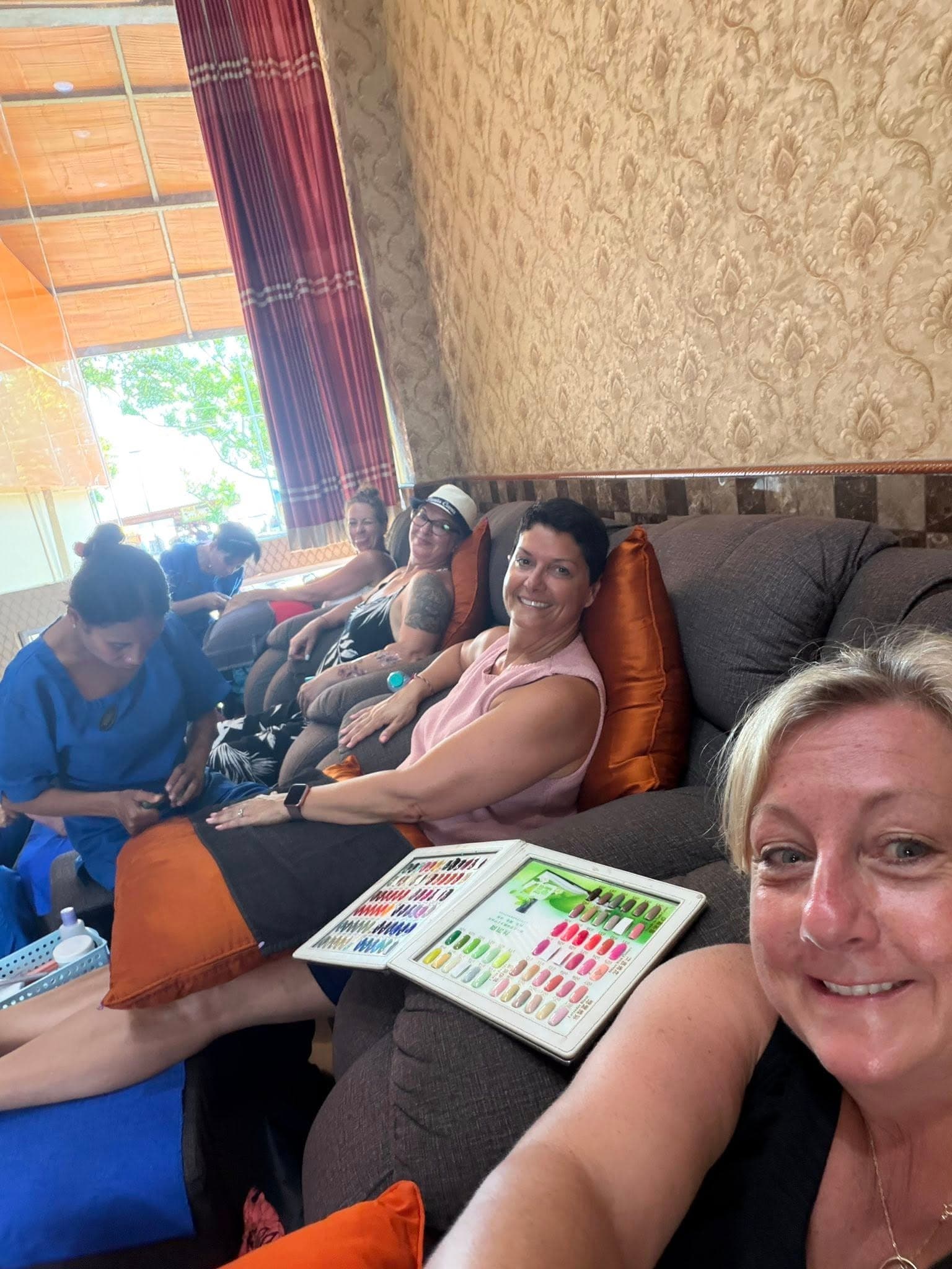 Group of women sitting on a couch indoors examining nail polish color swatches together