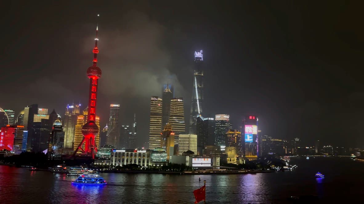 Shanghai skyline at night with illuminated Oriental Pearl Tower and modern skyscrapers reflected in the Huangpu River